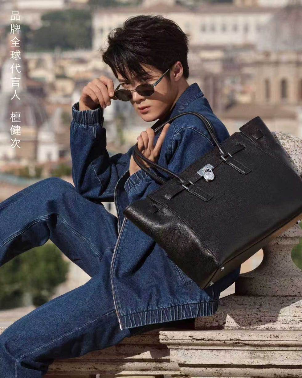 a person wearing a denim outfit sits with a stylish black handbag