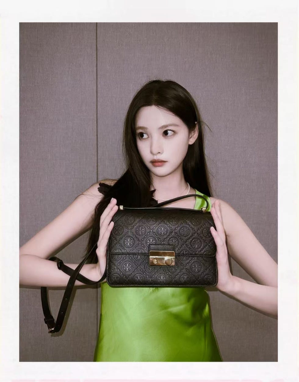 a person holding a designer handbag against a neutral background