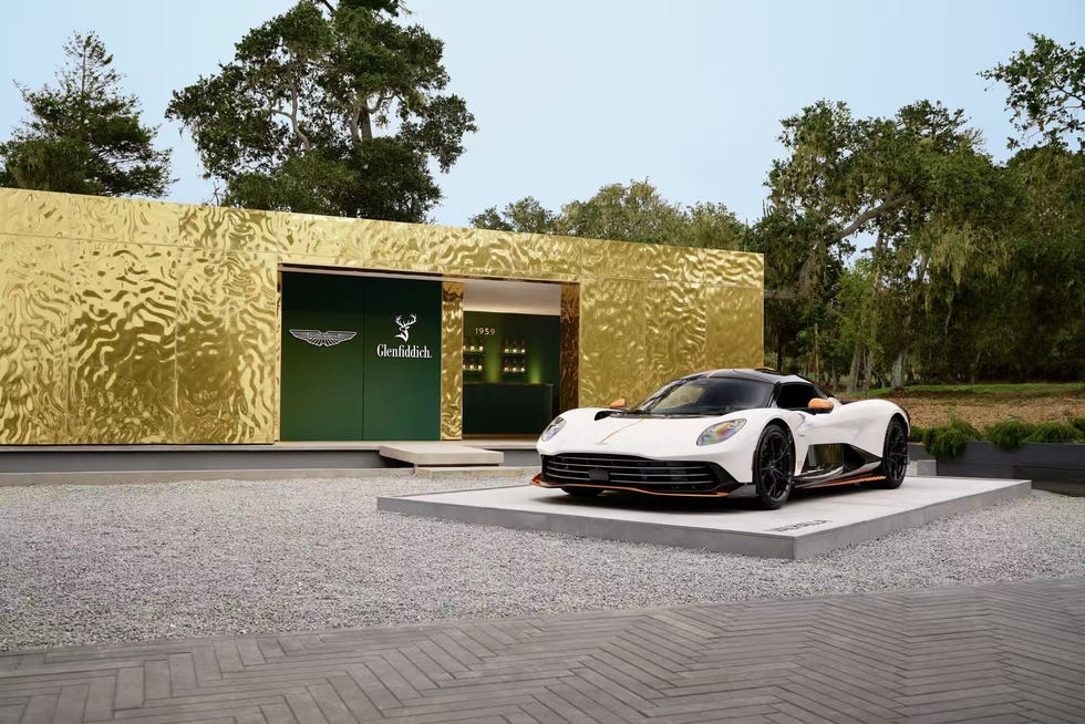 luxury car displayed in front of a modern golden exterior structure with branding