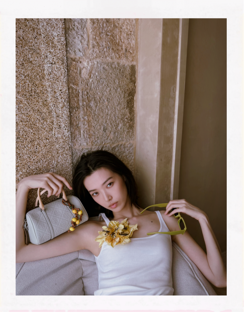 a person lounging on a sofa with a floral decoration and a stylish bag