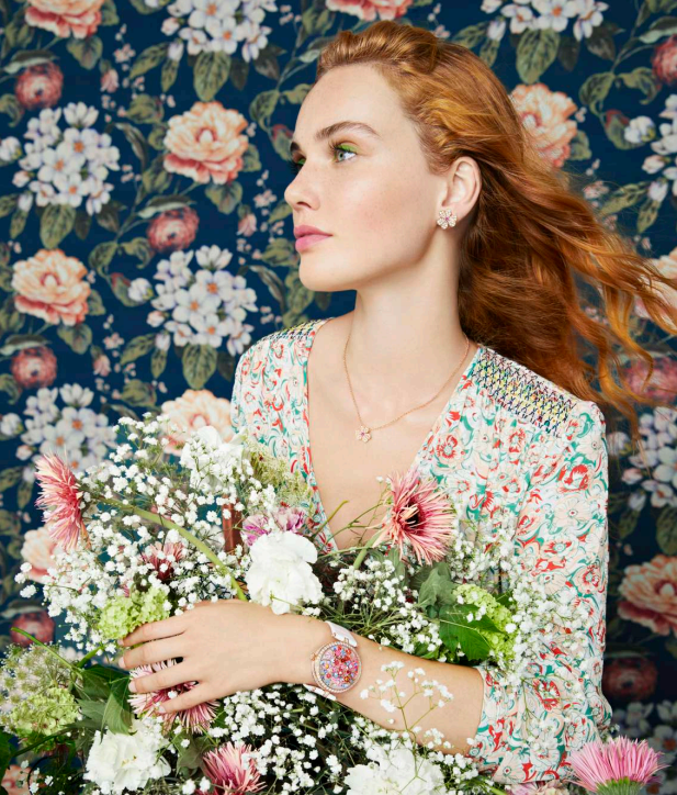 a person holding a large bouquet of flowers against a floral backdrop