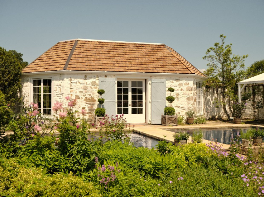 garden shed with a stone exterior and wooden roof in a lush garden