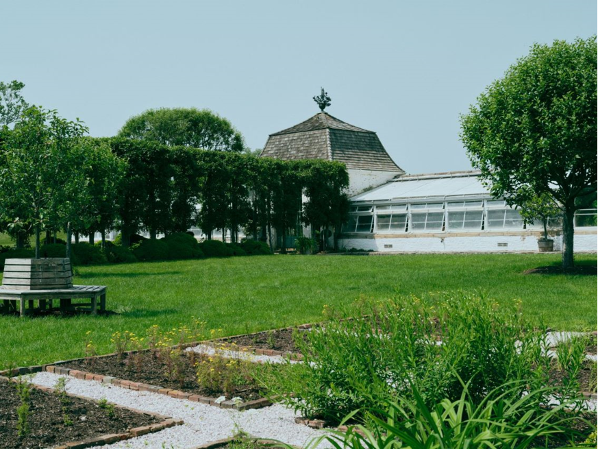 garden landscape featuring a greenhouse and gravel pathways
