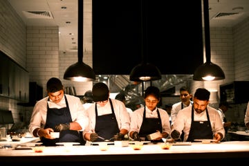 a group of chefs preparing dishes in a professional kitchen environment