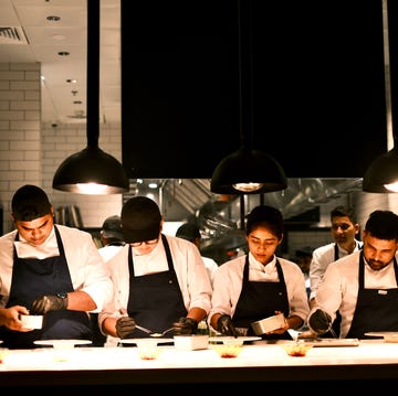 a group of chefs preparing dishes in a professional kitchen environment a group of chefs preparing dishes in a professional kitchen environment