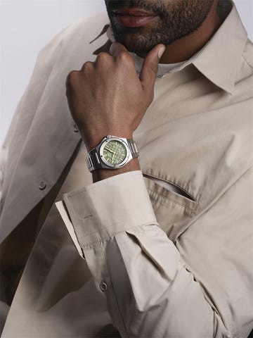 wristwatch on a persons hand highlighting a stylish green dial