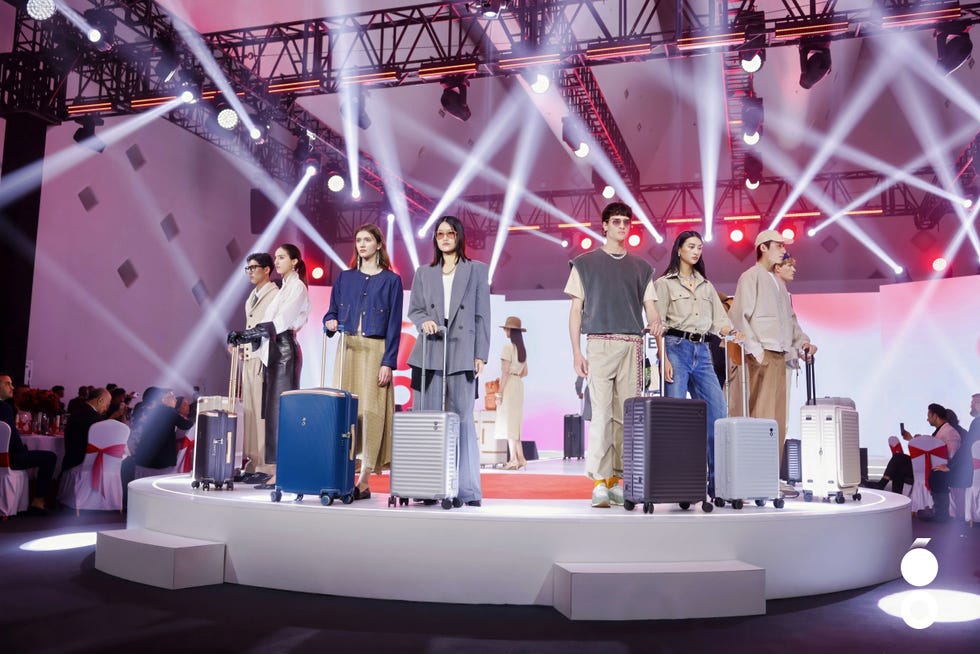 fashion showcase featuring models with luggage on stage