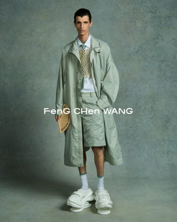 the scene features an individual in an oversized light green trench coat layered over a collared shirt and shorts