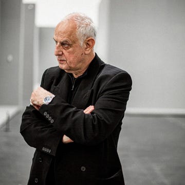 a person with crossed arms standing in a minimalist indoor space