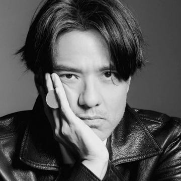 person in a black leather jacket resting their chin on their hand