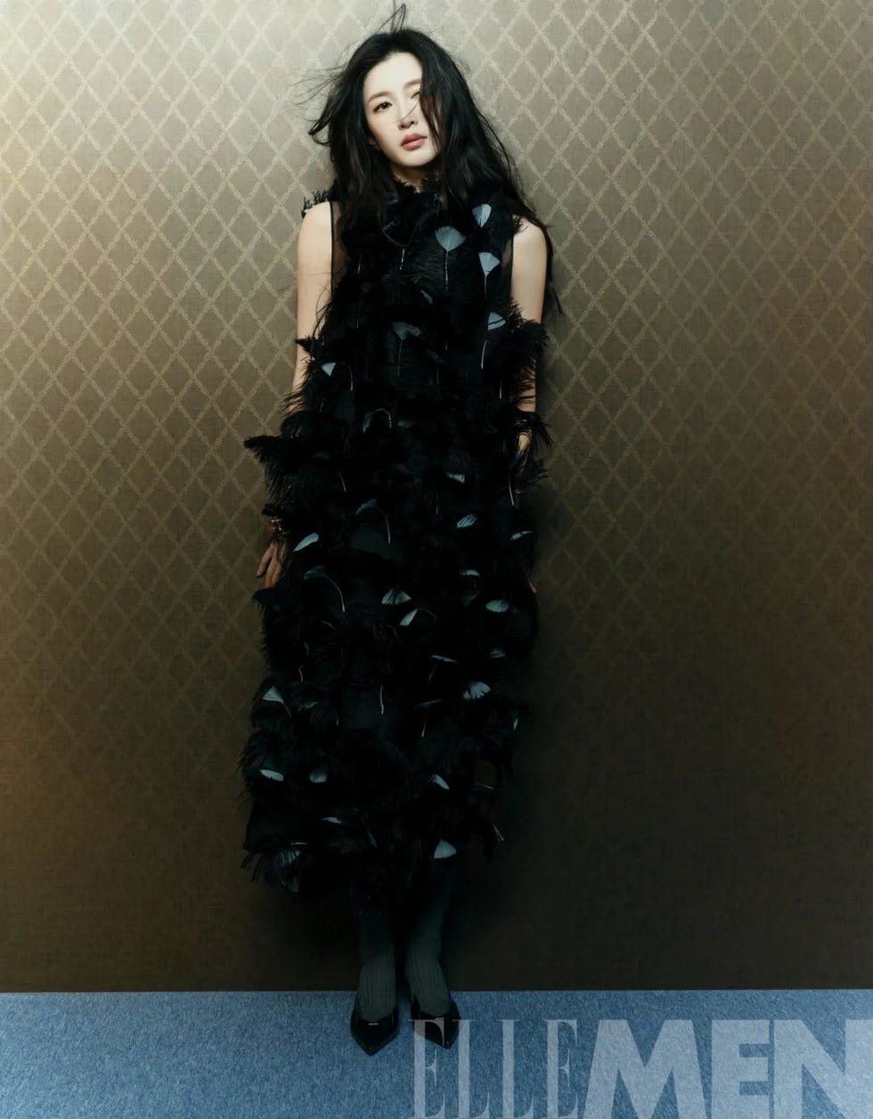 fashion model wearing a unique black outfit against a textured backdrop