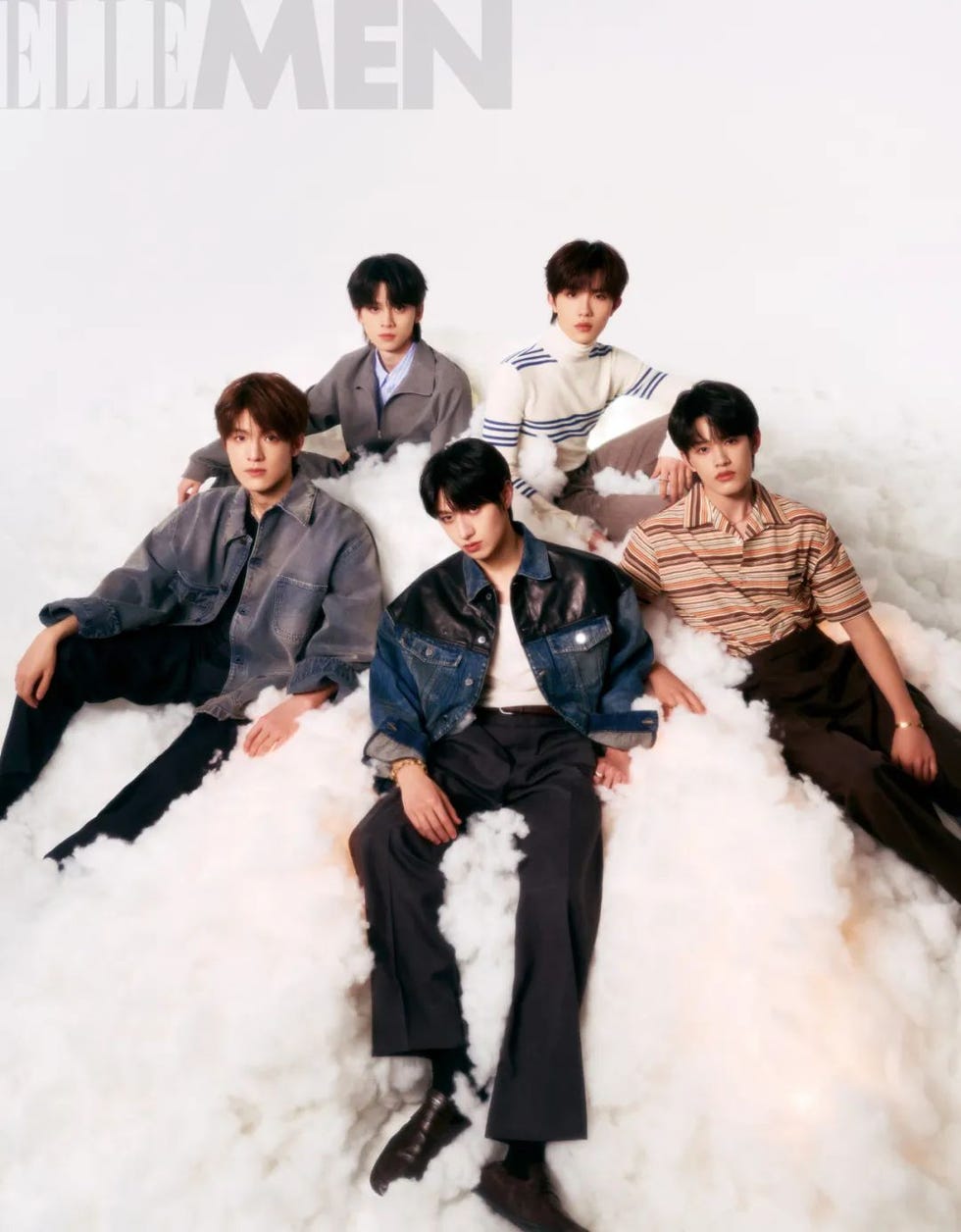 group of five individuals seated on a cloudlike surface styled for a fashion shoot