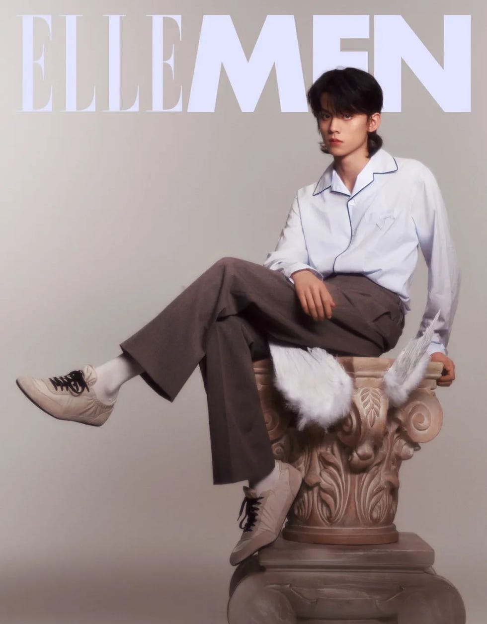 a male model sitting on a classical column wearing stylish attire