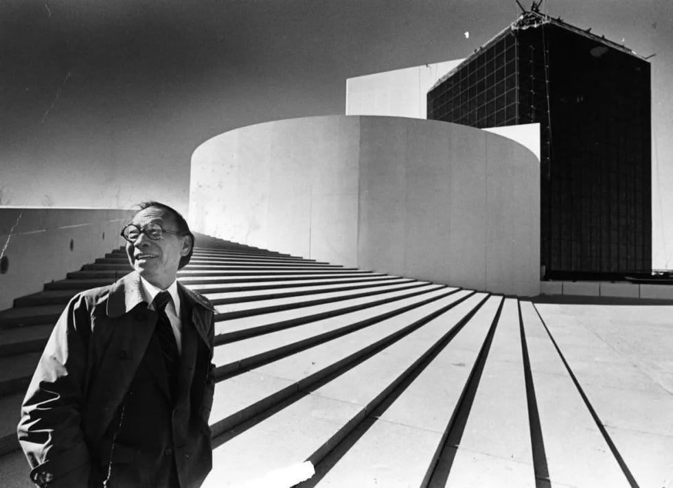 a person stands near architectural structures featuring stairs and a modern building