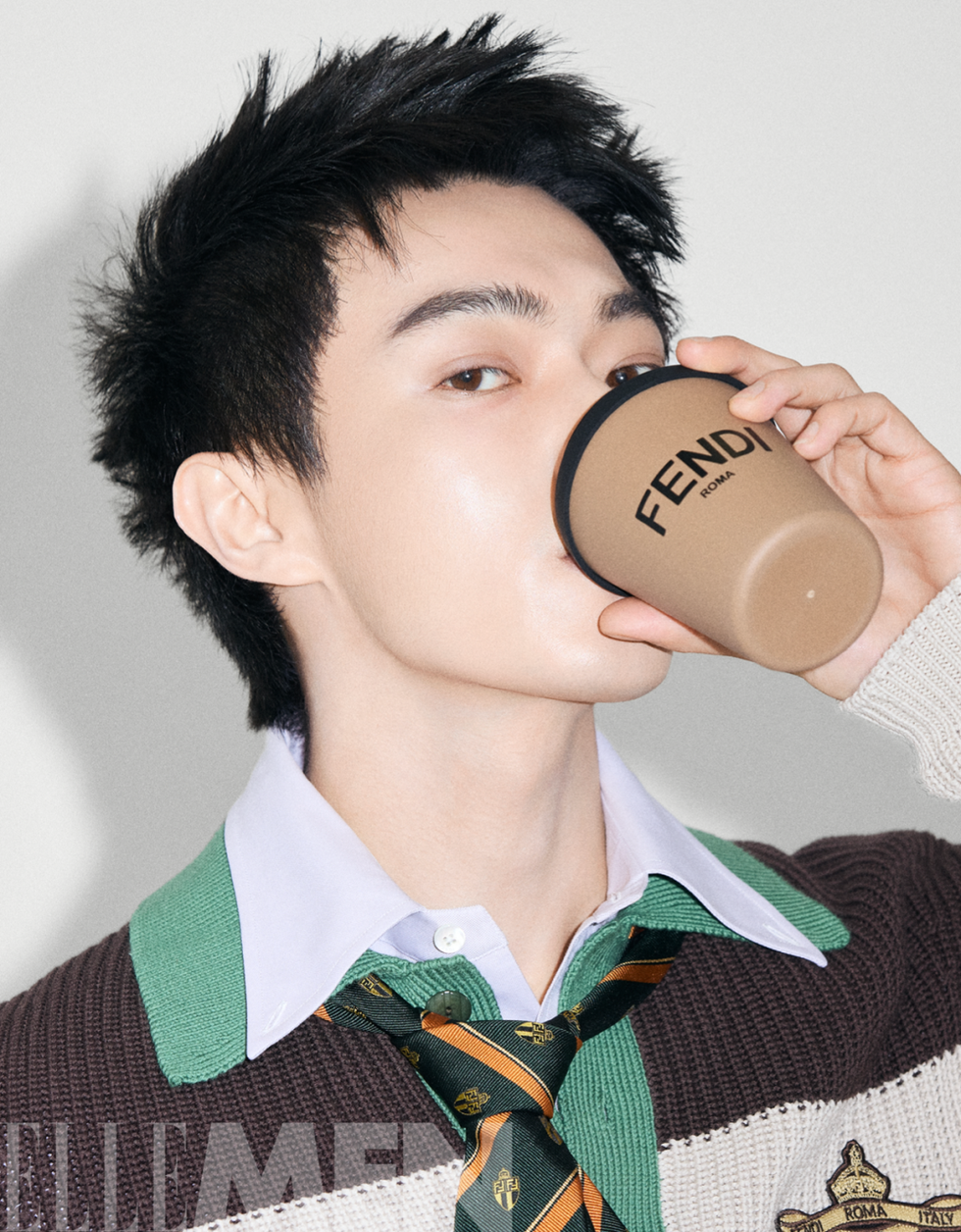 person in a sweater and tie holding a drink