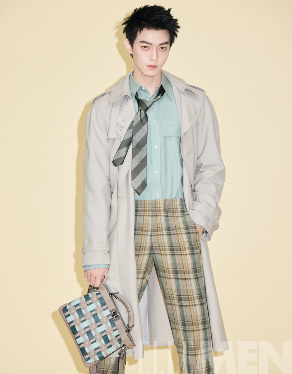 fashion model in a stylish outfit showcasing a trench coat patterned shirt and plaid trousers with accessories
