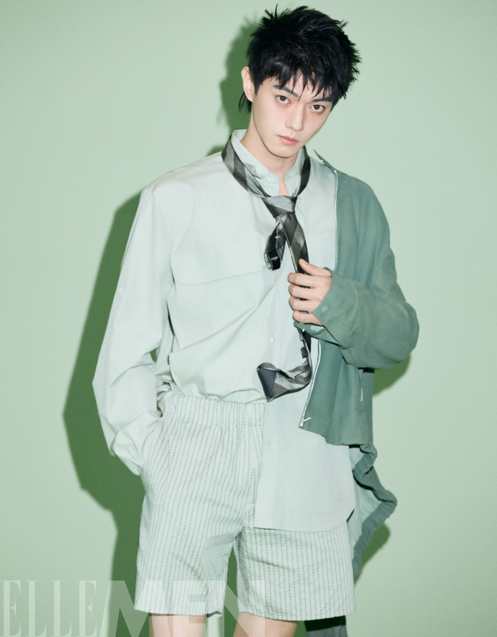 a person wearing a light green outfit styled with a tie and shorts