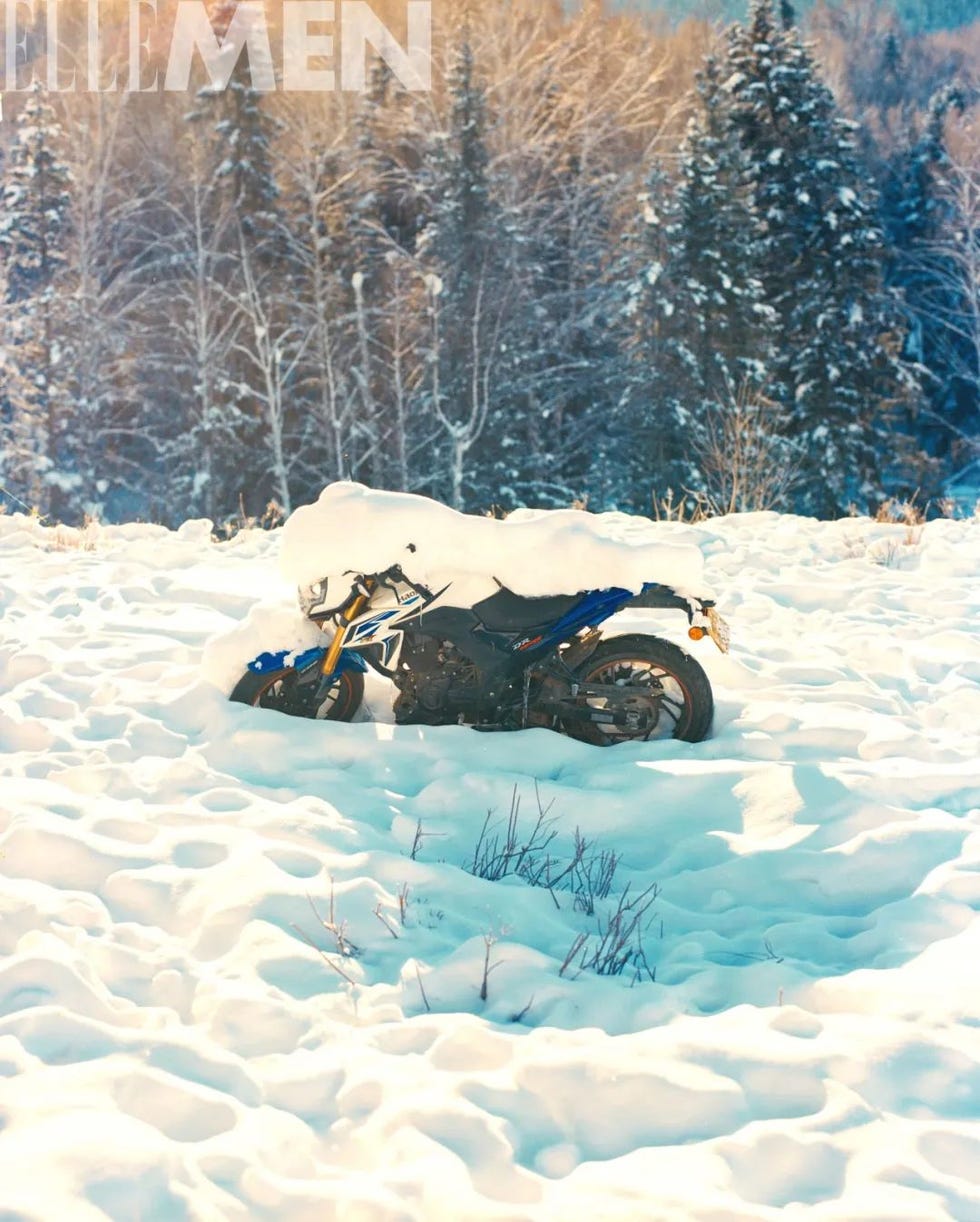 a motorcycle partially buried in snow in a forested area