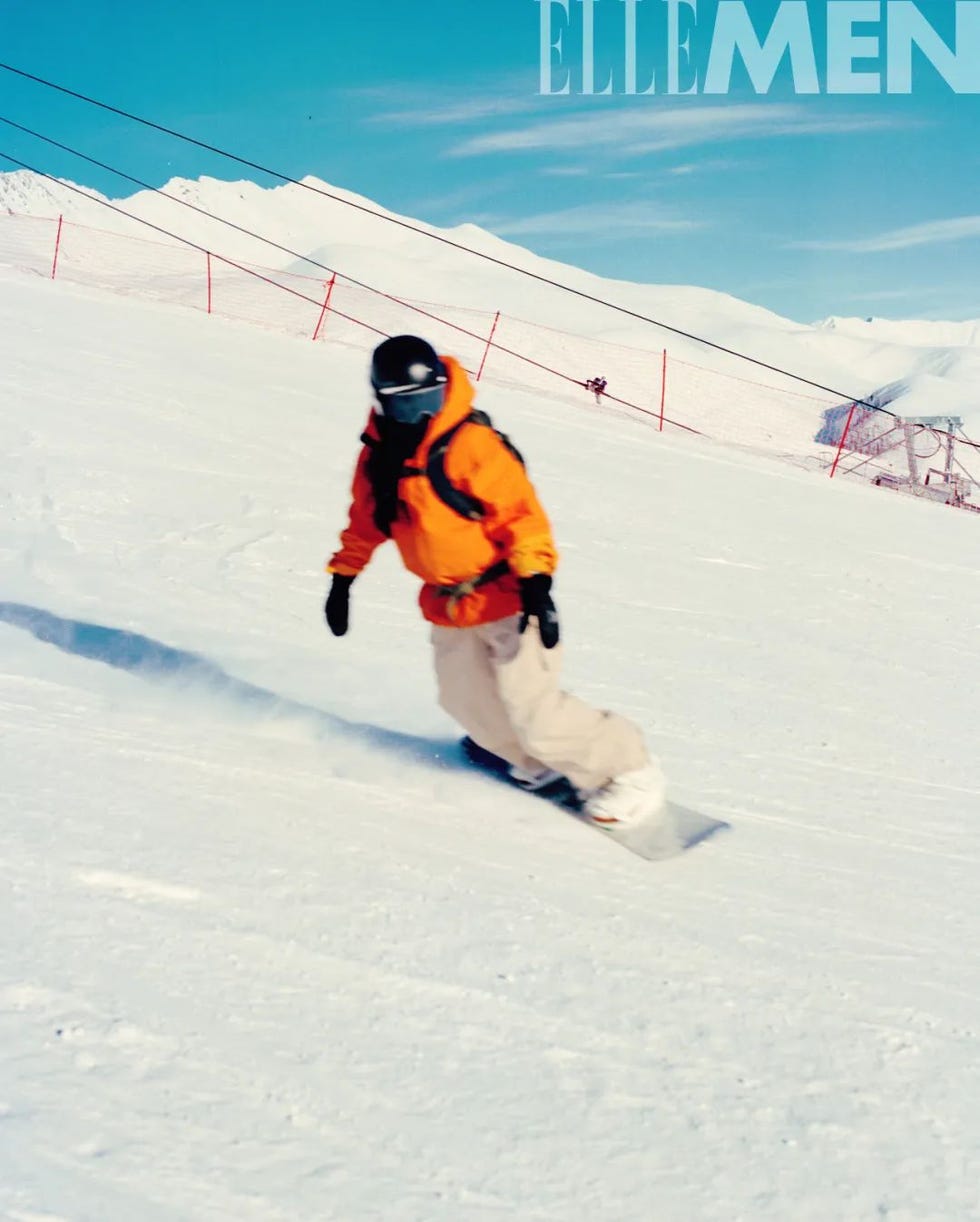 snowboarder descending a snowy slope in bright orange gear
