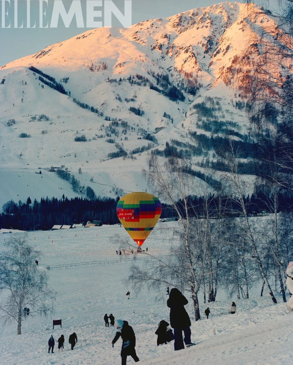 colorful hot air balloon descending over a snowy landscape with people enjoying winter activities
