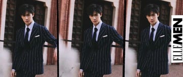a man in a pinstriped suit standing confidently in an outdoor setting with architectural elements