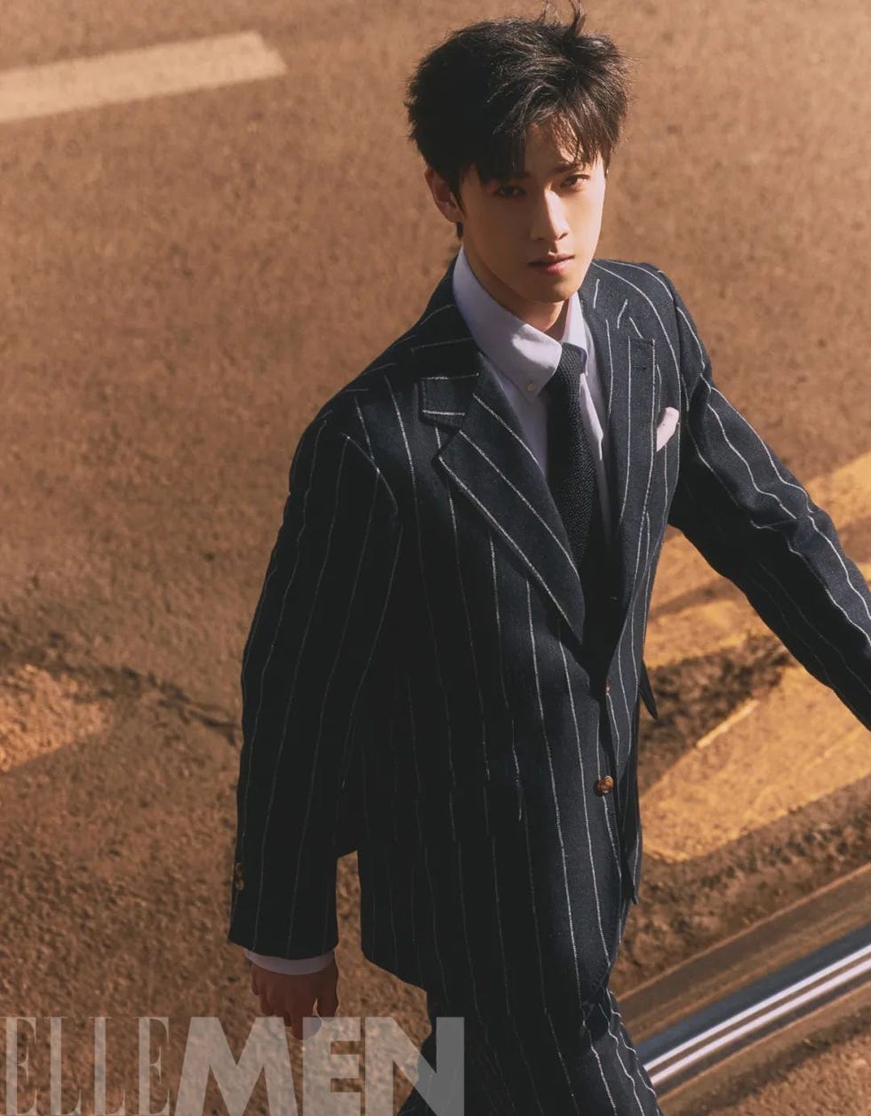 man in a pinstripe suit walking along a street
