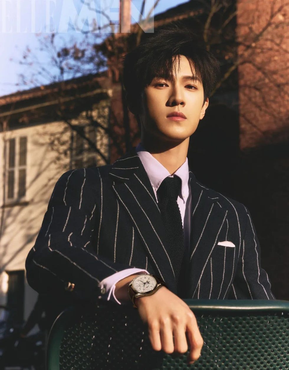 a stylish individual wearing a pinstriped suit with a watch posing casually