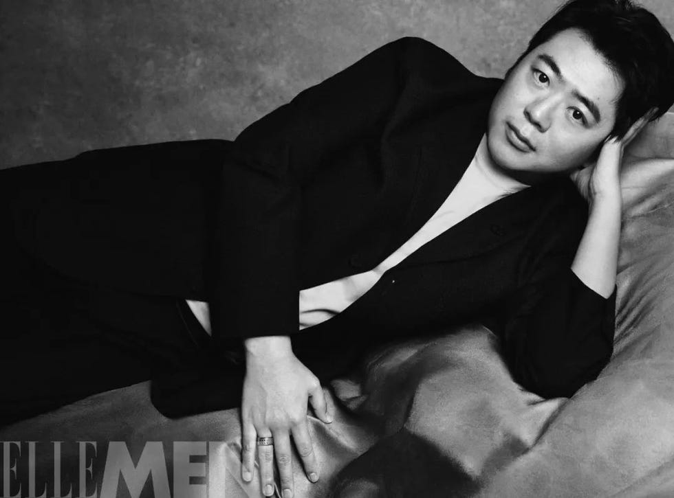 a person lying on a satin surface wearing a black suit