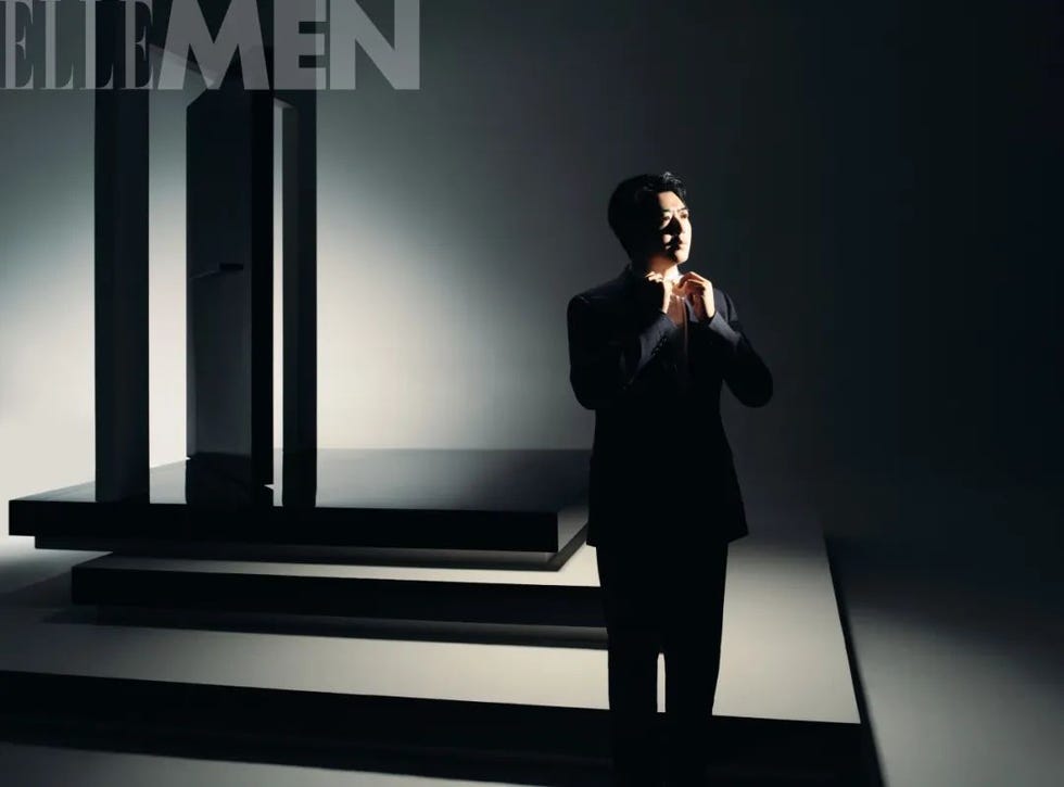 a man adjusting his tie illuminated against a dimly lit background