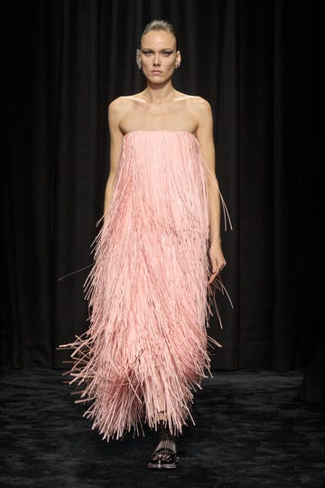 Fashion model showcasing a unique pink fringe gown on a runway