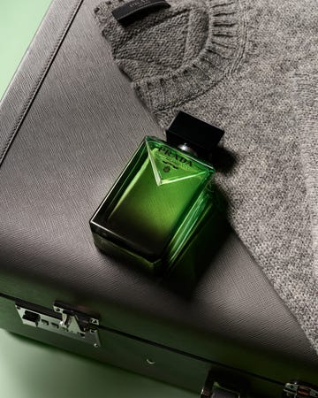 prada fragrance bottle displayed with a gray sweater and a textured black case