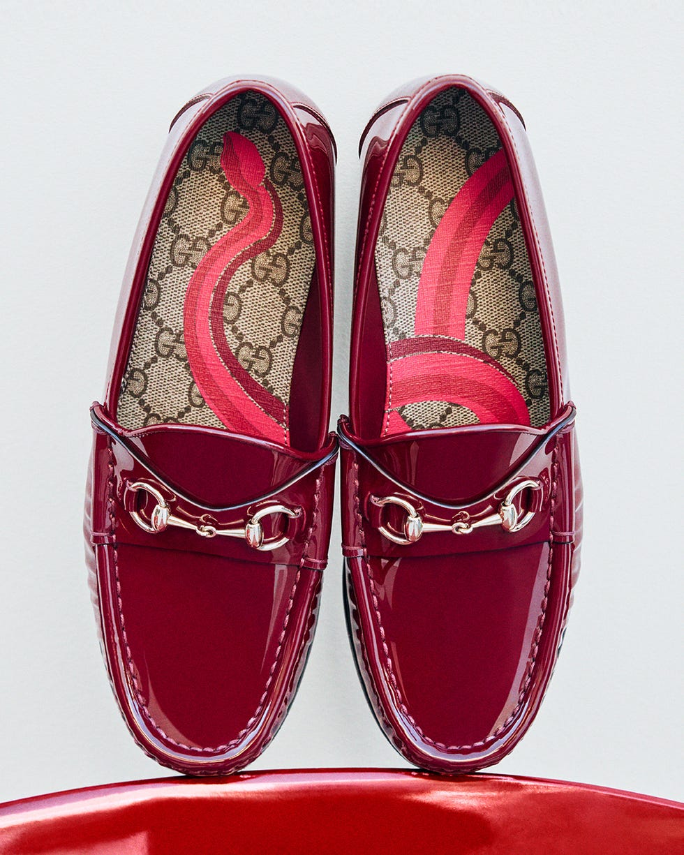 pair of glossy burgundy loafers with a decorative chain detail and branded interior