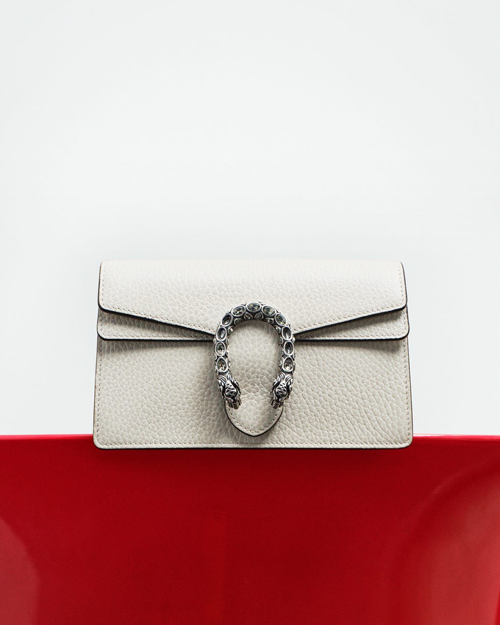 fashion accessory featuring a textured lightcolored leather handbag with a distinctive clasp