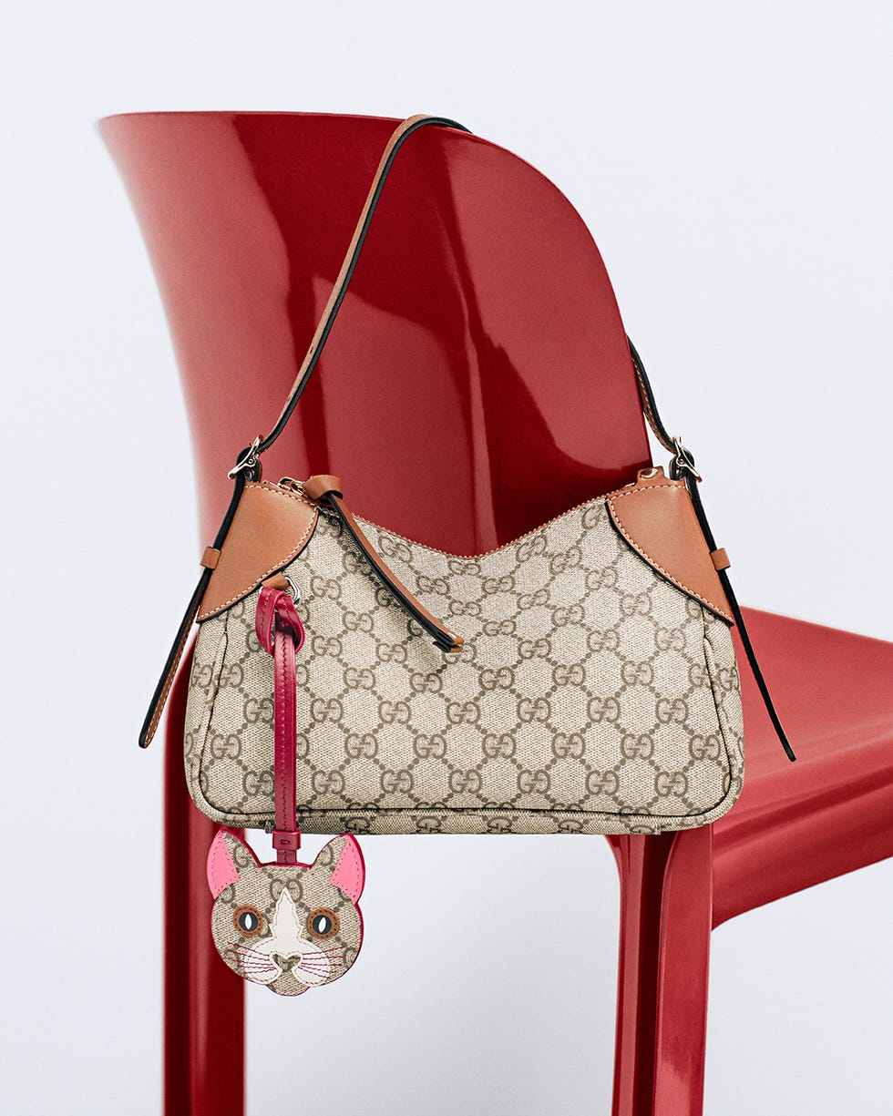 designer handbag with a catshaped charm on a red chair
