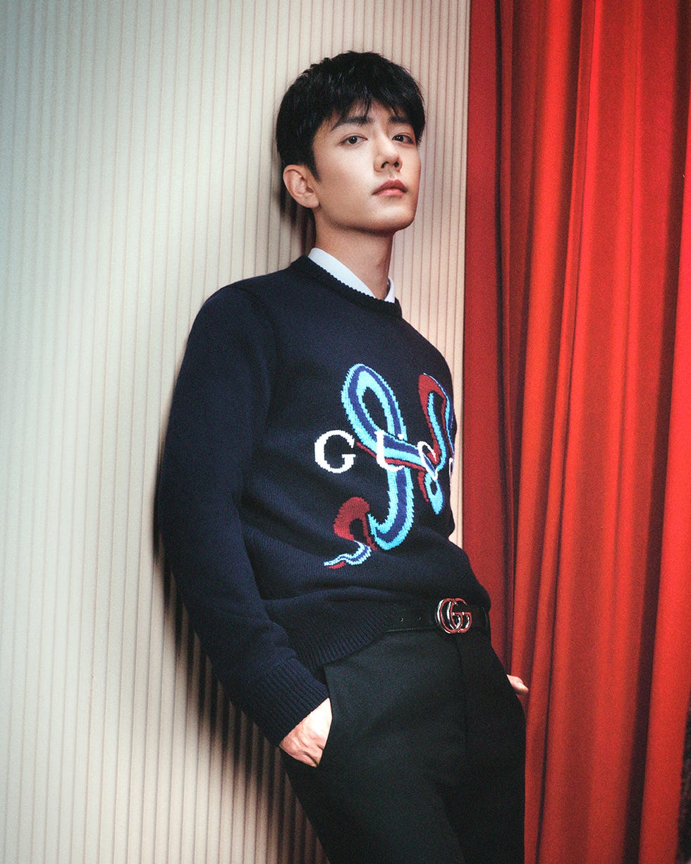 stylish individual wearing a patterned sweater and dress pants