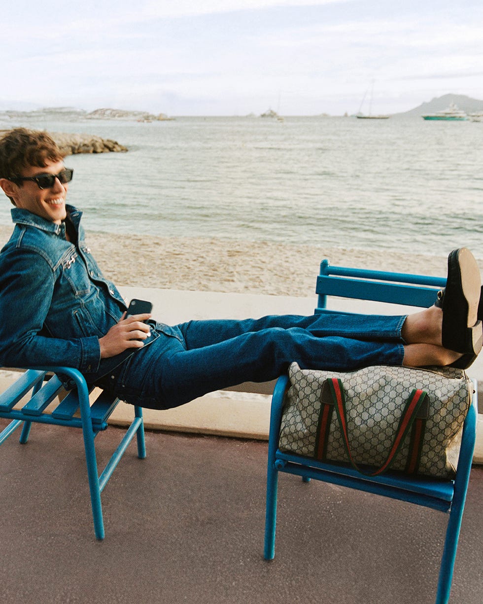 person lounging by the seaside with legs resting on a bag