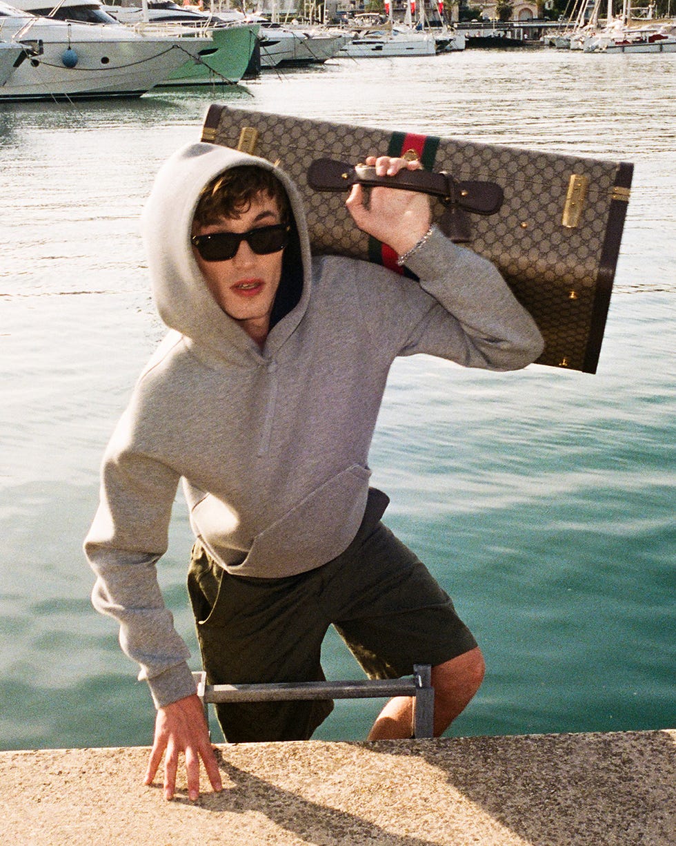 person entering water while carrying a designer bag