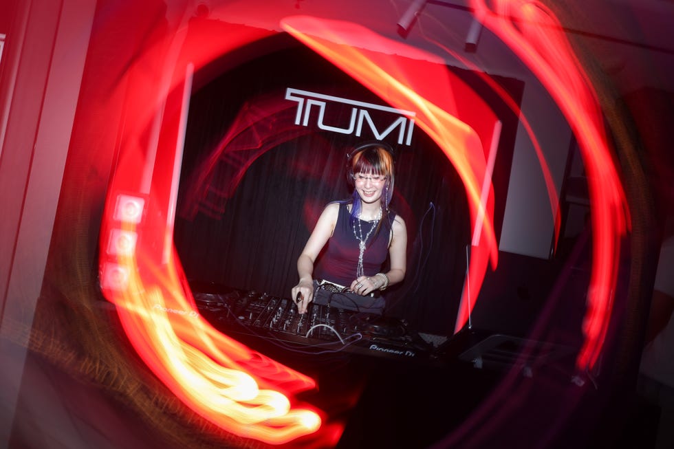 dj performing live with vibrant light trails in a nightclub scene