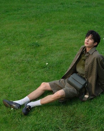 a person relaxing on a grassy area dressed in casual outdoor attire