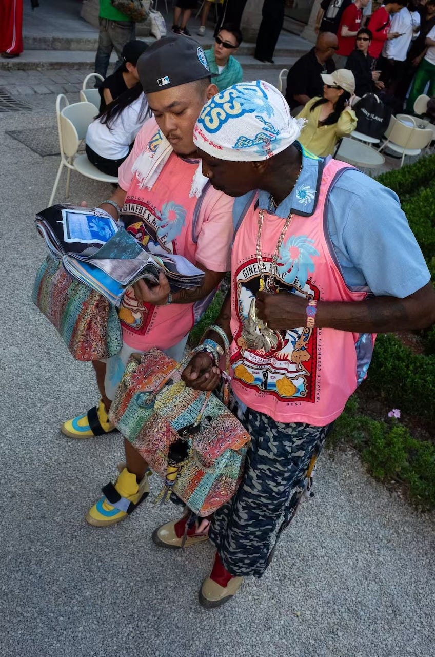 two individuals dressed in colorful attire holding bags and magazines