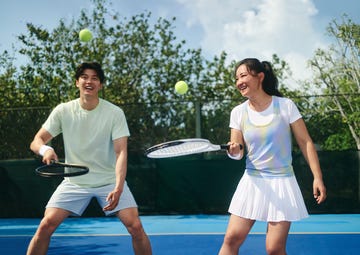 two individuals practicing tennis on a court