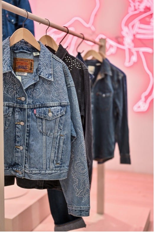 denim jackets displayed on a hanger with neon background