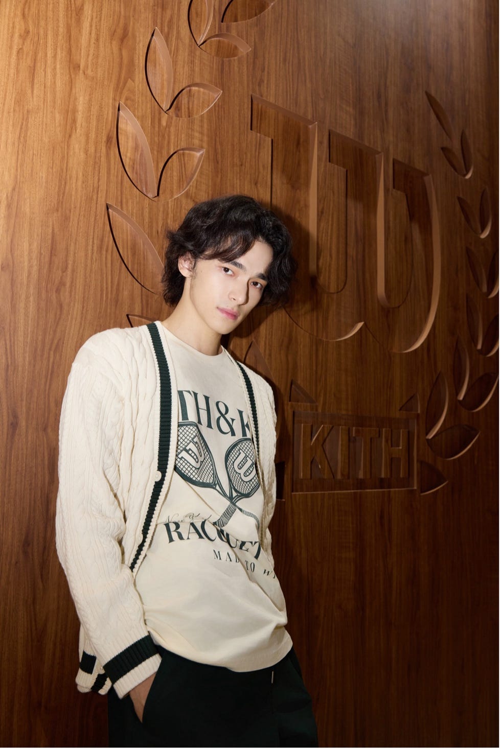 individual posing against a wooden wall with brand logos