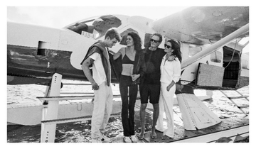 group of four individuals standing near a seaplane on water