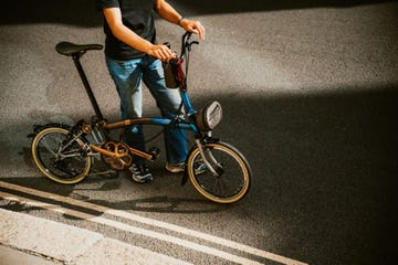 person standing with a folded bicycle on a street