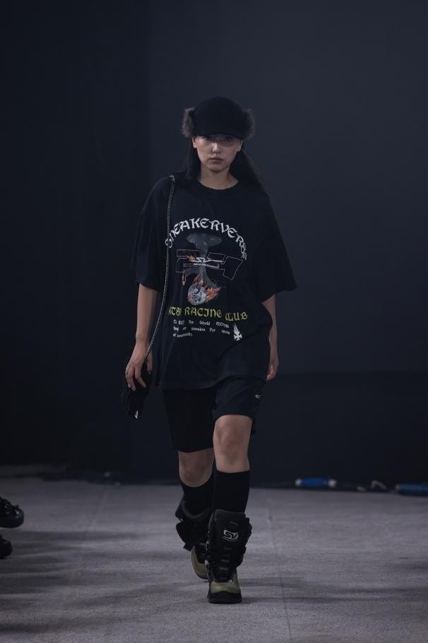 model walking on runway wearing a graphic oversized tshirt and sports shorts