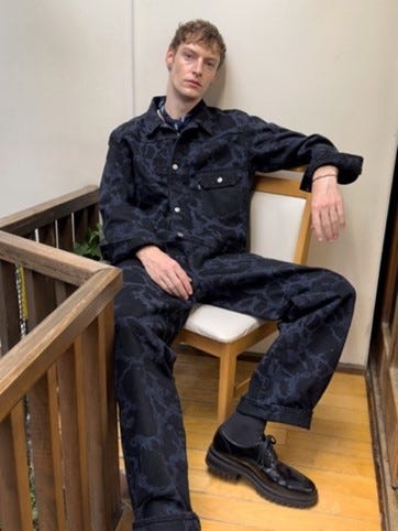 individual seated on a chair dressed in a patterned denim outfit