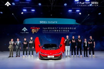 a group of people standing next to a red car