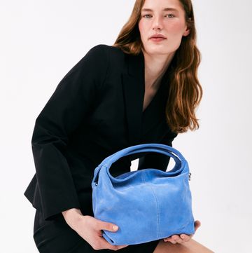 a person sitting on the floor holding a blue purse