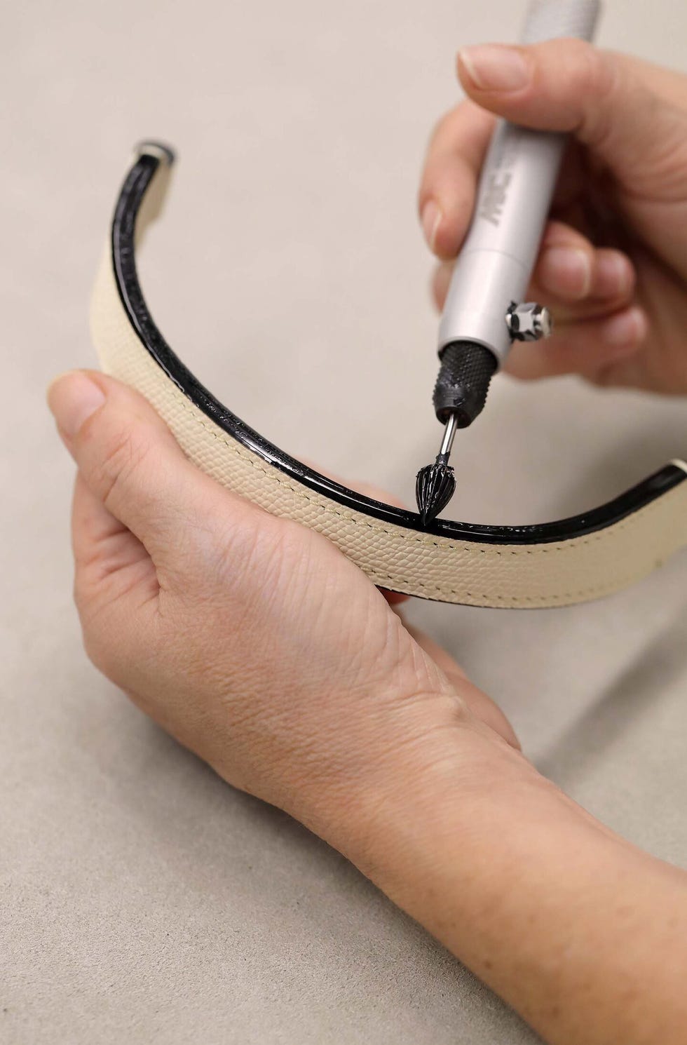 hand holding a piece of leather and a tool for detailing